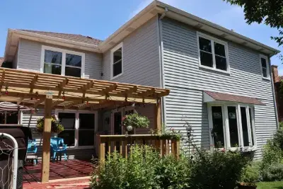 Back of a two-story home in Naperville, IL with new white double-hung windows and a bay window, labels still on the glass after installation